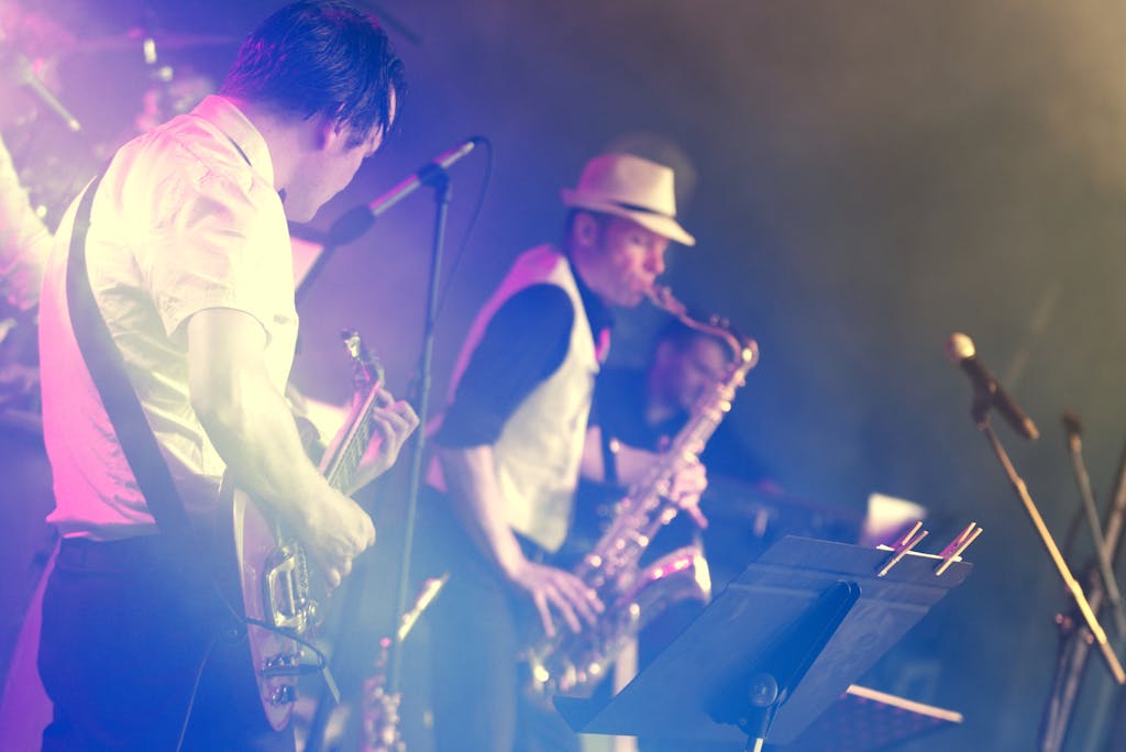 Actuación vibrante en el escenario con un guitarrista y un saxofonista en un concierto en vivo enérgico.